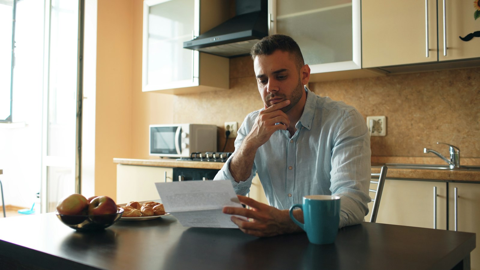 A business owner reading a letter at his kitchen counter